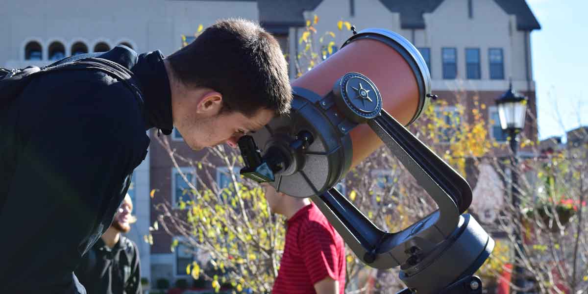 A student looks through a telescope in Astronomy class