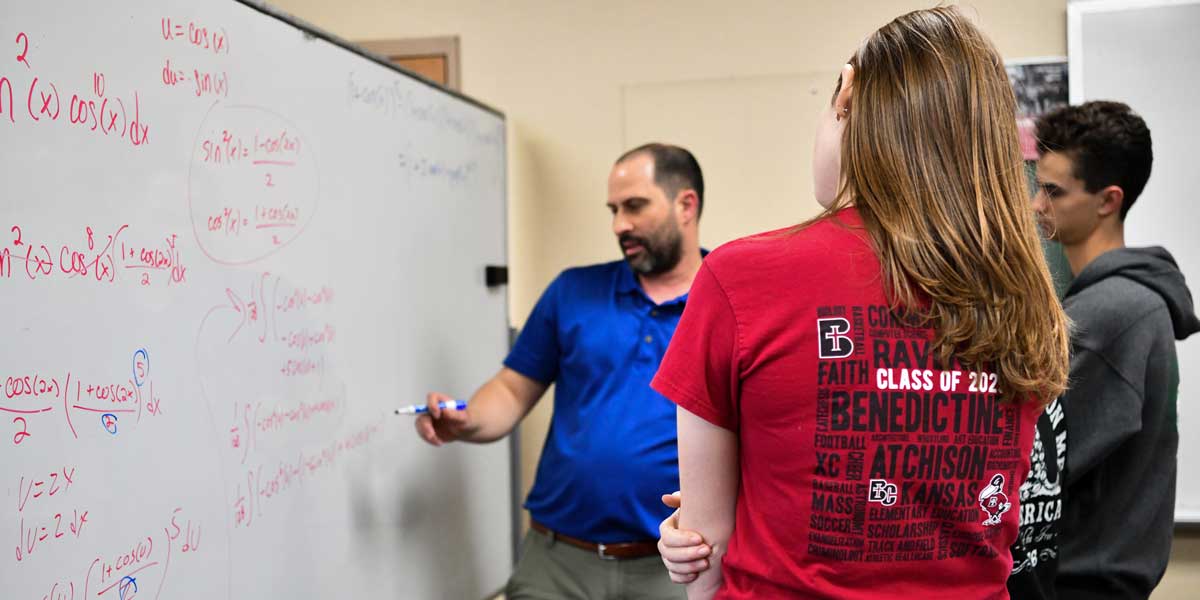 Math professor Dr. Hein teaching a student calculus on a whiteboard