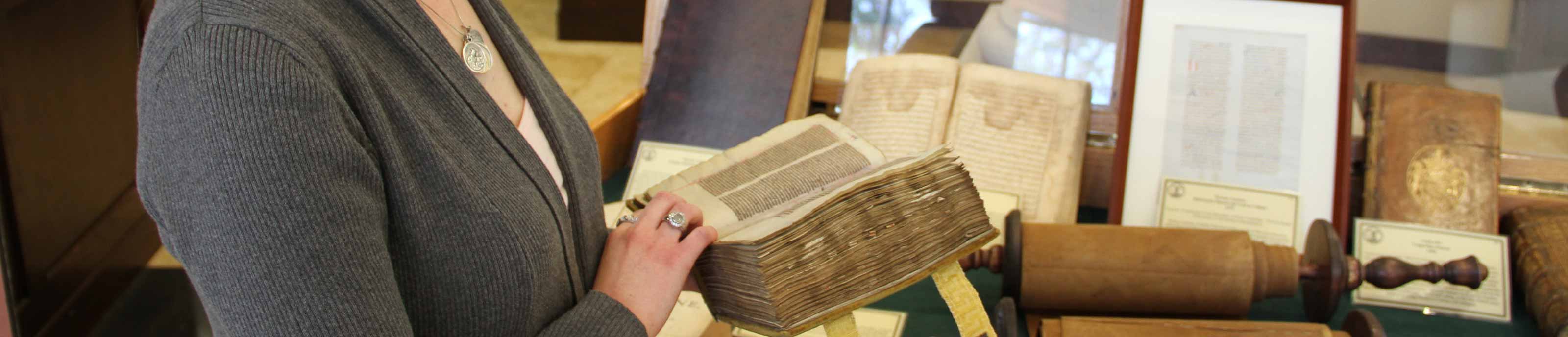 Student examining an old tome during the Wisdom of the Ages exhibit