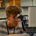 A student looks through an eyepiece in a lab