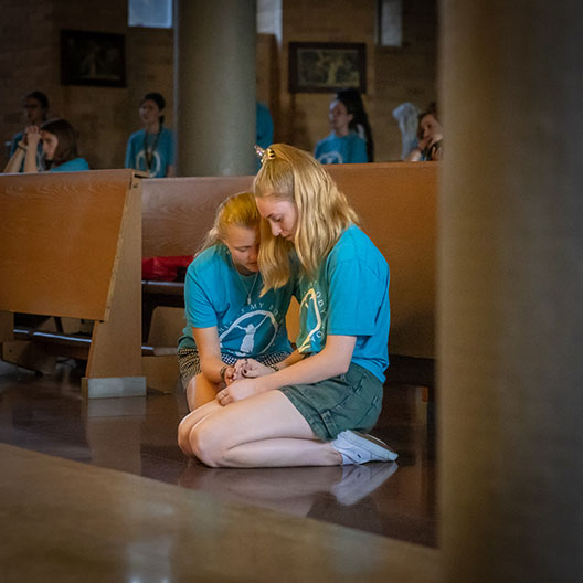 Two BCYC students comforting each other while praying in the abbey's guadalupe chapel 