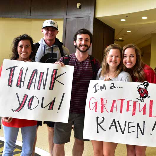 Students holding thank you signs during Grateful Raven Day