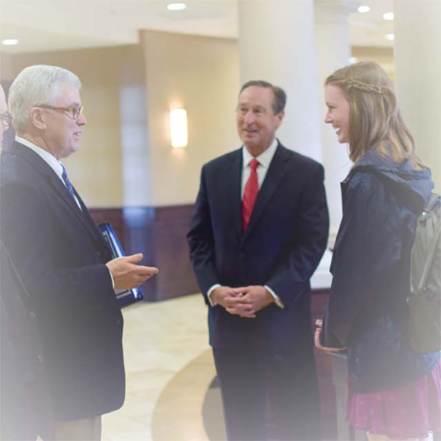 A student converses with President Minnis and another man
