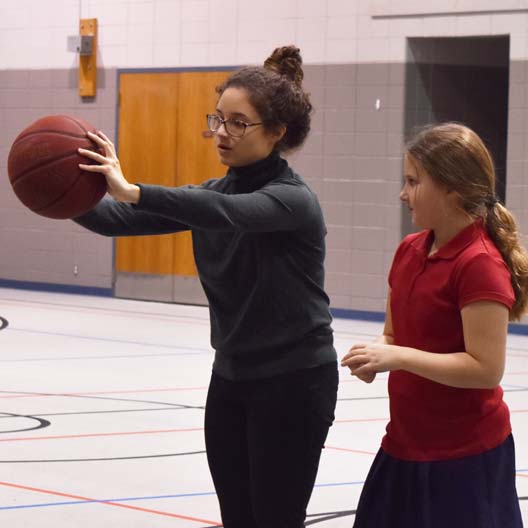 A student playing with a basketball at a primary education service-learning Physical Education class