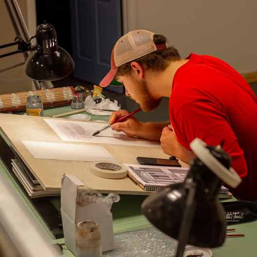 A student works at a drafting table