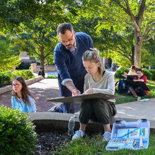 John Haigh assists a student in an outdoors Architecture class