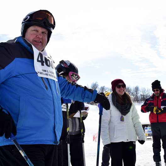 A Special Olympics athlete in ski gear, with a Benedictine College student volunteer nearby