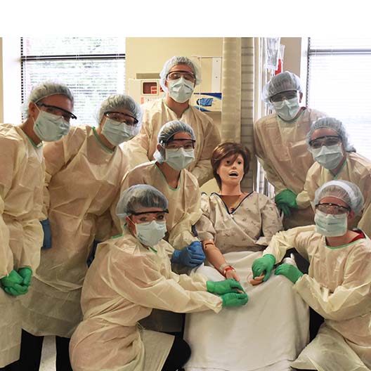 Nursing students in scrubs with a fake patient