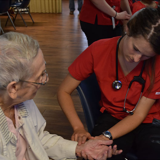 Nursing student taking pulse of an elderly patient