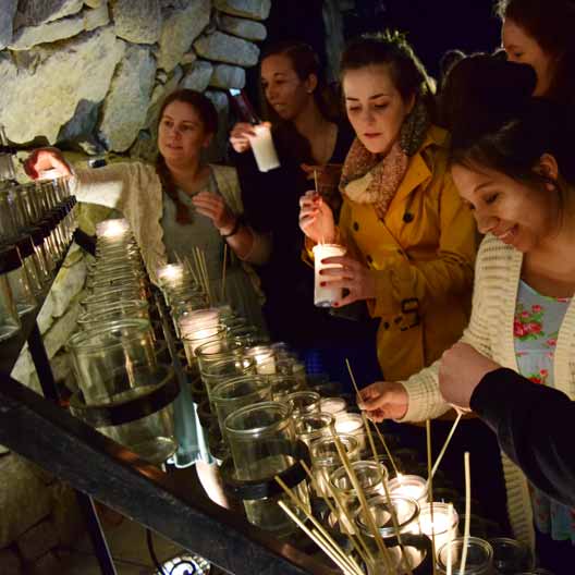 Students lighting candles at Mary's Grotto