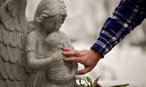 A student's hand touching a statue of a child held by an angel