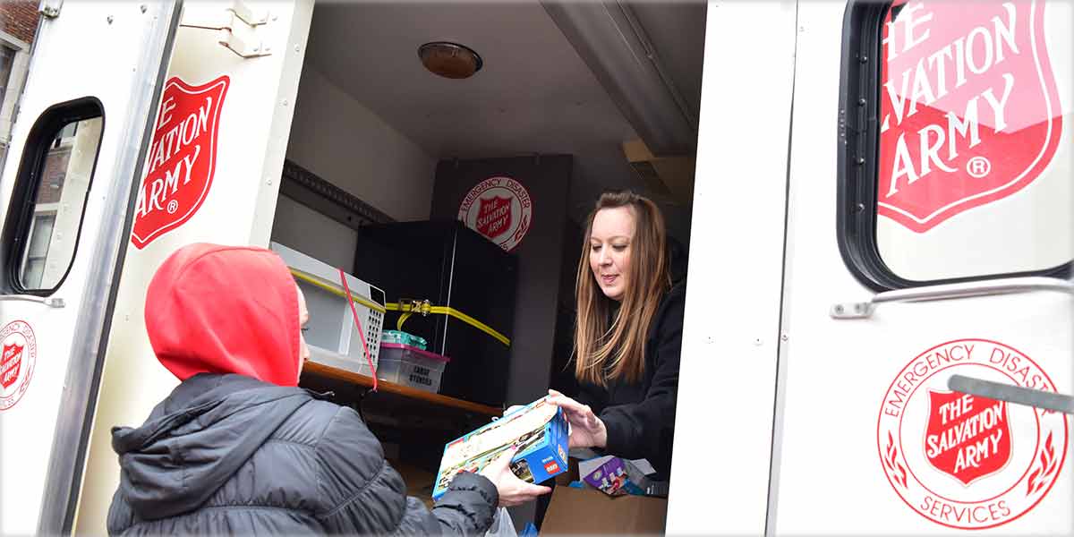 A student hands a toy to a person in a Salvation Army truck