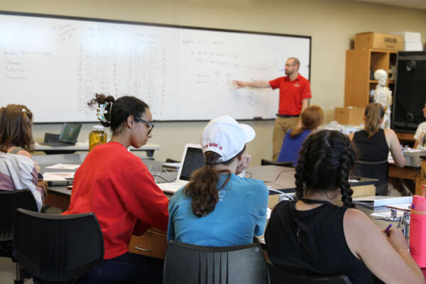 A professor teaches students in a lab