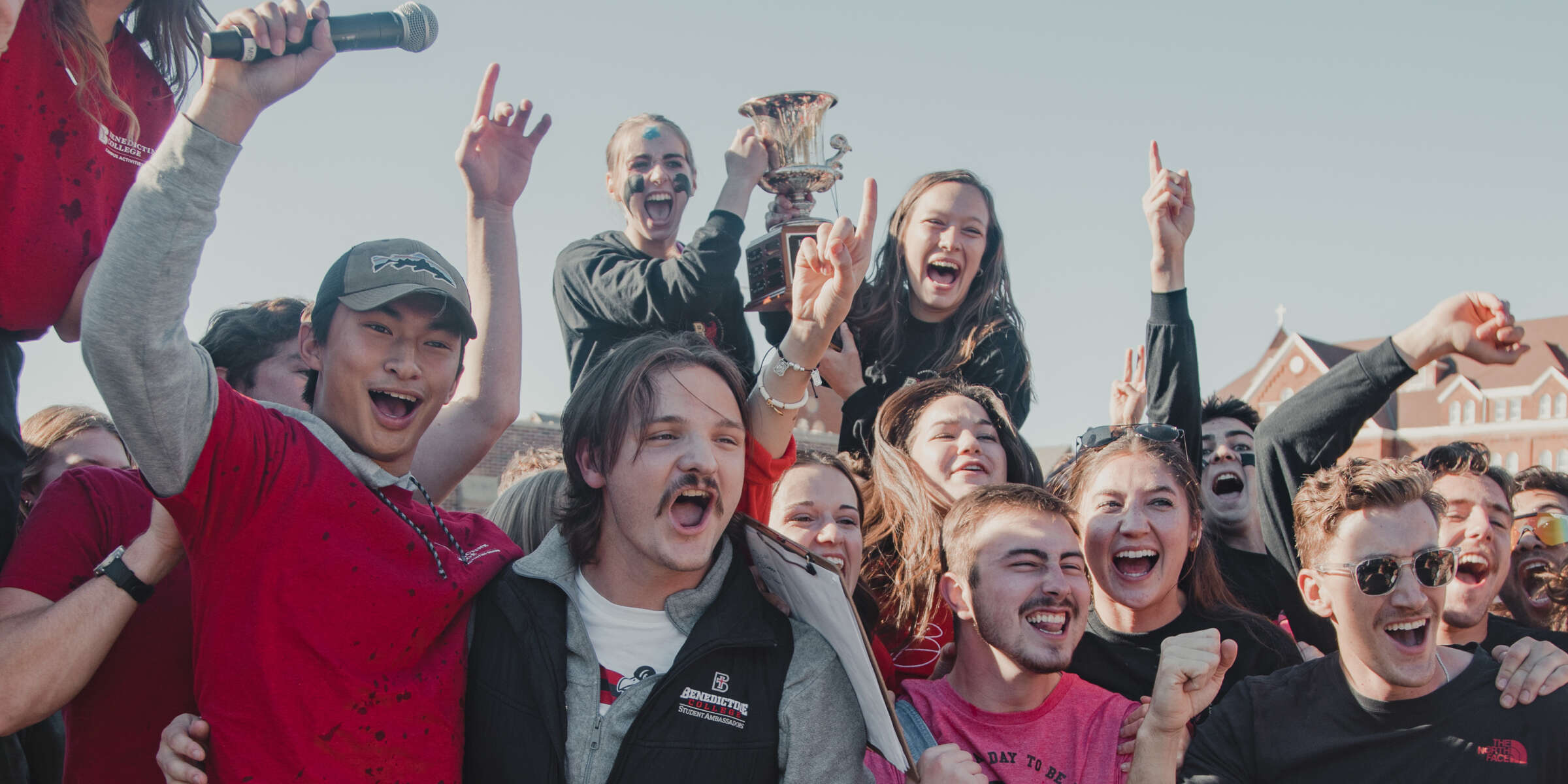 Students cheer and hold a trophy during Homecoming celebrations